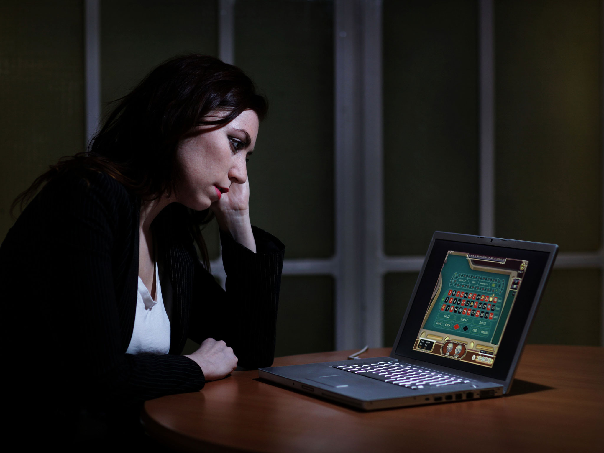 Woman gambling on laptop online at a table