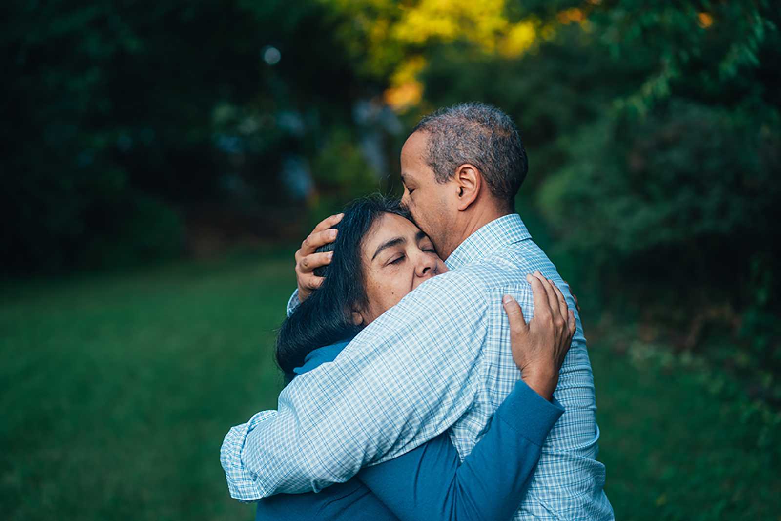 Testimonials page - older couple embracing in a garden grove in the summertime